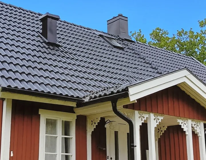Komplett takbyte med mörka takpannor på rött trähus